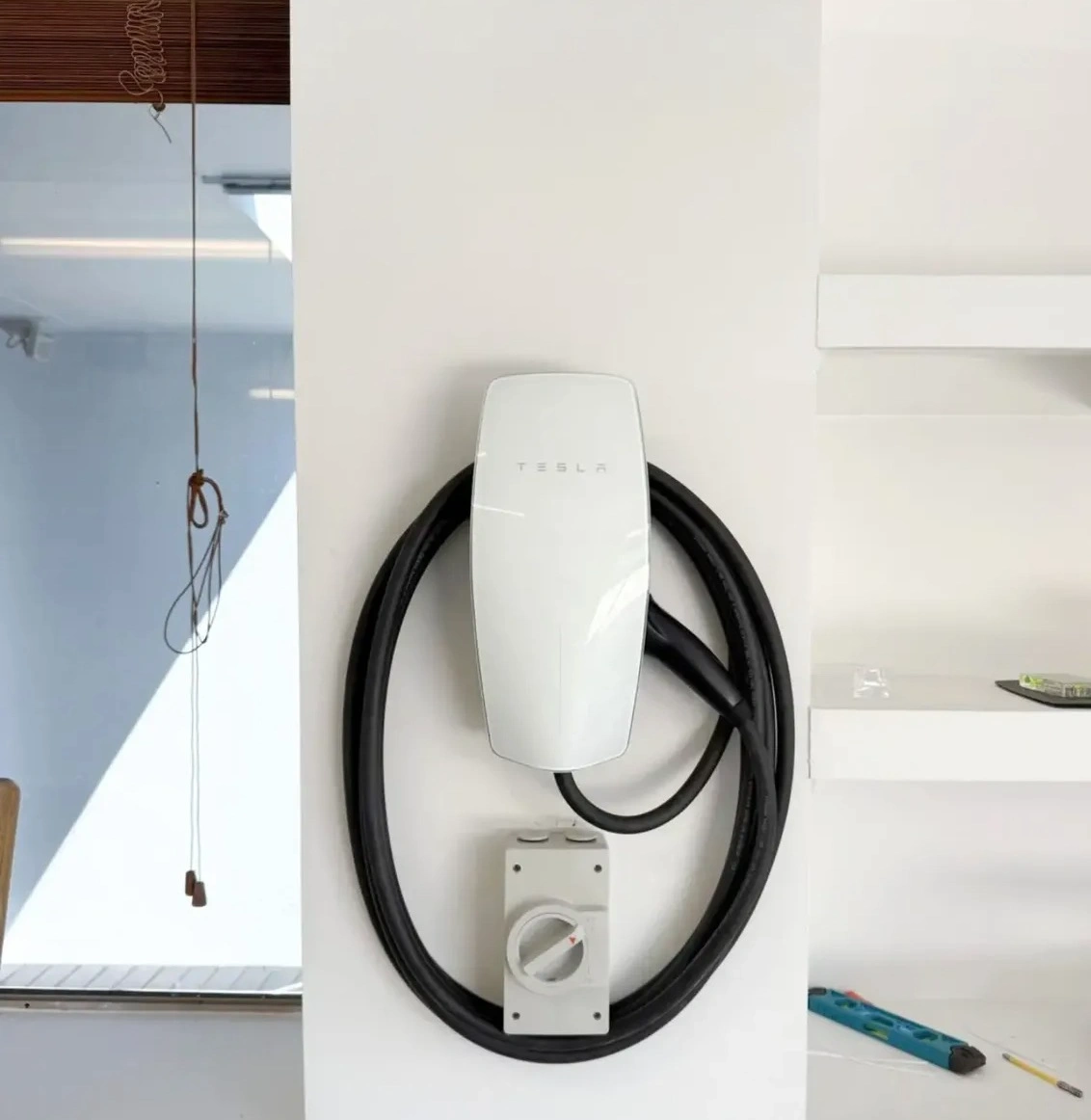 White EV charger installed beside its isolation switch